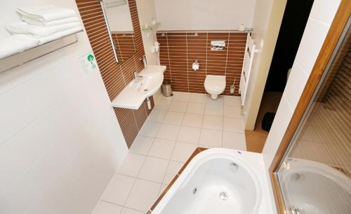 a bathroom with a tub and a toilet and a sink at City Hotel Nitra with free parking in Nitra