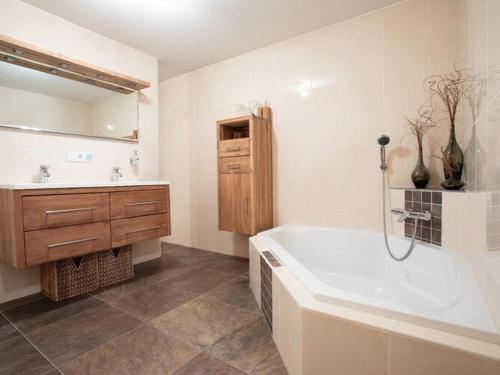 a bathroom with a tub and a sink and a mirror at Chalet Hochkrimml with sauna on the ski slope in Nothdorf