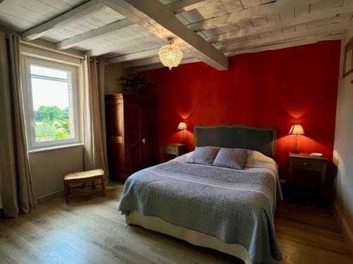 a bedroom with a bed with red walls and a window at Le Mas De Marie in Lavaur