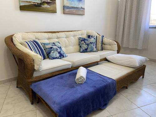 a wicker couch in a living room with a table at Ap charmoso na beira da praia do Centro | ROMM101 in Rio das Ostras