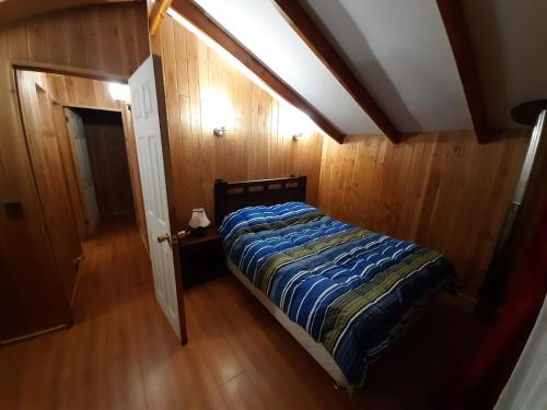 a bedroom with a bed in a room with wooden walls at Cancel in Pucón