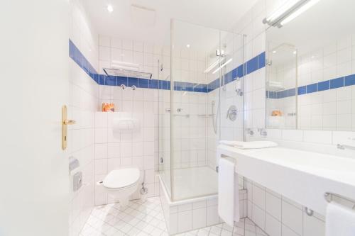 a white bathroom with a shower and a toilet at Hotel Kontorhaus Stralsund in Stralsund