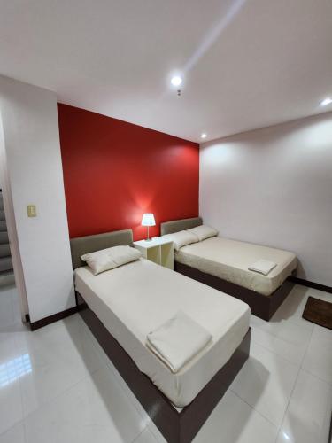 two beds in a room with a red wall at MANTRA PENSIONNE Standard Room in Cagayan de Oro