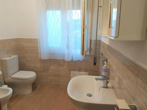 bagno con lavandino, servizi igienici e finestra di B&B Casa Valentina a Linguaglossa a Linguaglossa
