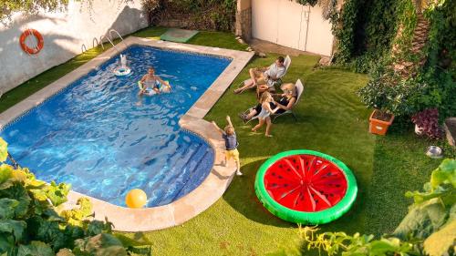 a group of people sitting around a pool with a watermelon at Villa del Jerte in El Torno