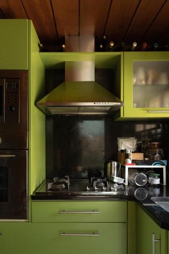 a kitchen with green cabinets and a stove top oven at Encantadora moradia T1, com piscina e vista mar a 500m da praia in Viana do Castelo