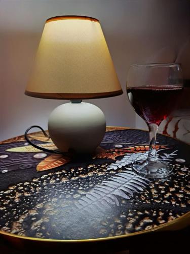 a table with a lamp and a glass of wine at Studio Apartman K2 in Trebinje
