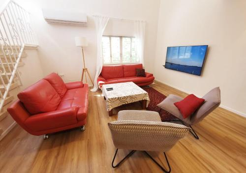 a living room with two red couches and a table at Spacious 3BD Penthouse with Rooftop & Parking in Ra‘ananna