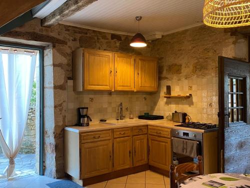 - une cuisine avec des placards en bois et une cuisinière dans l'établissement L’Hirondelle, à Castelnaud-la-Chapelle
