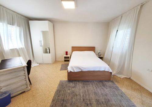 een slaapkamer met een bed, een dressoir en ramen bij Spacious 3BD Penthouse with Rooftop & Parking in Ra‘ananna