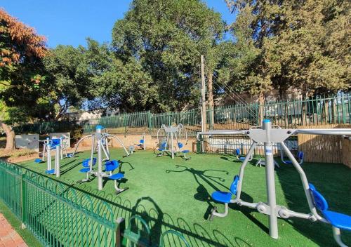 a playground with blue chairs in a park at Spacious 3BD Penthouse with Rooftop & Parking in Ra‘ananna