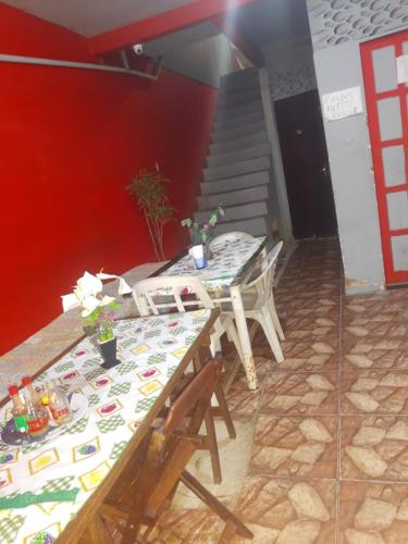 two tables and chairs in a room with a staircase at Mel Pousada in Macaé