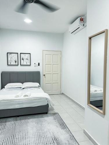 a white bedroom with a bed and a mirror at Homestay Ar-Rayyan 3 Ketereh in Ketereh