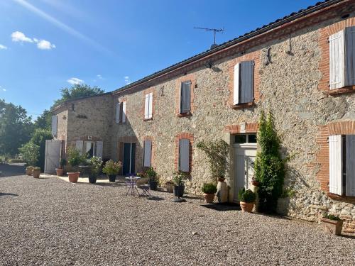 a large stone building with potted plants in front of it at Le Mas De Marie in Lavaur
