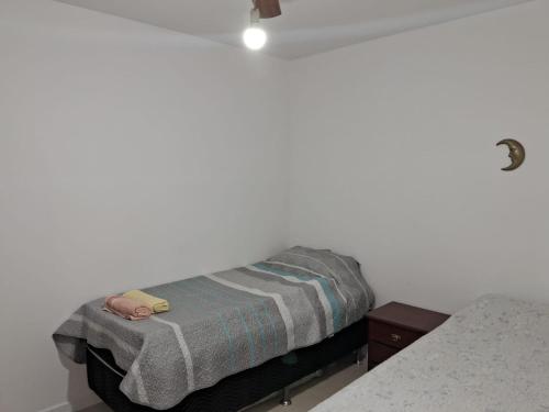 een klein bed in een witte kamer met een deken bij APTO LINDO FRENTE PRAIA GRANDE in Arraial do Cabo