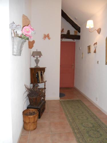 a hallway with a red door and flowers on the wall at Ferme les Rousseaux in La Belliole