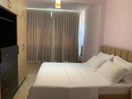 1 dormitorio con 1 cama blanca grande y TV en Arbi's Pool View Apartment, en Golem