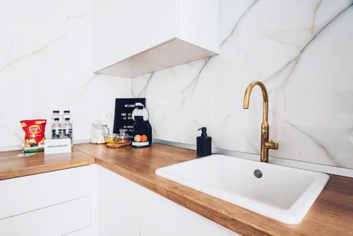a white kitchen with a sink and a counter at VOYA Apartments - a luxury oasis in the old town in Braşov
