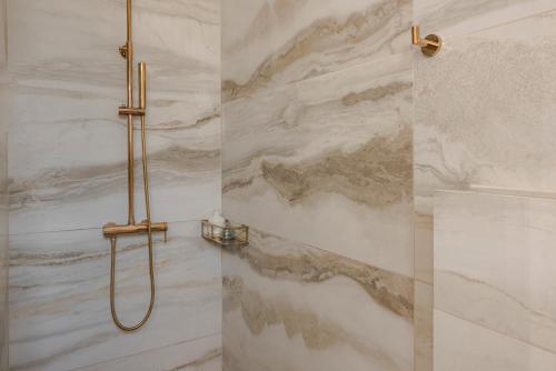 La salle de bains est pourvue d'une douche et de murs en marbre. dans l'établissement Sea View Villa Kefaloniaprivatevillas, à Karavádhos