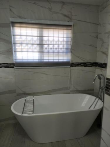 a white bath tub in a bathroom with a window at Josmot Guest House in Gaborone