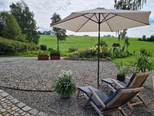 a patio with two chairs and an umbrella at Top modernes Appartement mit Blick ins Grüne in Kißlegg