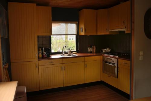 a kitchen with yellow cabinets and a sink and a window at Tukken op de Maashorst in Schayk