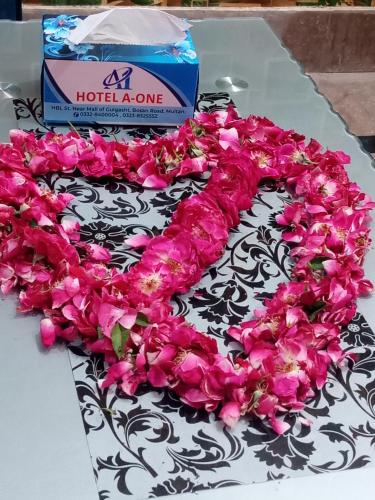 a cake with pink roses on a table with a box at Hotel A-One in Multan
