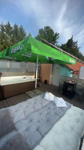 a large bed with a green umbrella on a deck at Bed and Breakfast Kreft in Ljutomer