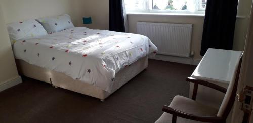 a bedroom with a bed with a white comforter and a window at Green Village Guest House - Near Manchester Airport in Sale
