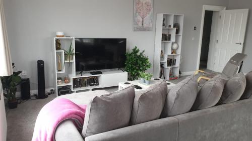 a living room with a couch and a flat screen tv at Spacious 2-Bed 2-Bath Apartment with Free Parking - Central Poole in Poole