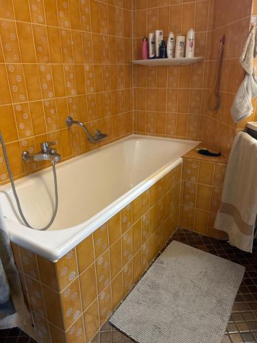 La salle de bains est pourvue d'une baignoire et de carrelage orange. dans l'établissement logement entier: appartement. Chez Gilbert Crans-Montana, à Crans-Montana