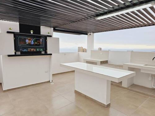 Habitación con mesas blancas y TV en la pared. en Exclusivo Dpto 101 Completo en Antofagasta, en Antofagasta