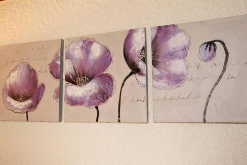 four paintings of purple flowers on a wall at Spacious Farmhouse Apartment, by Lake & Mountains in Larringes