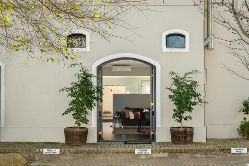 an open door into a white building with two potted plants at Luxury Franschhoek getaway next to Winetram in Franschhoek