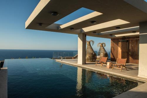 een huis met een zwembad en twee stoelen bij Happy Cretan Suites in Agia Pelagia