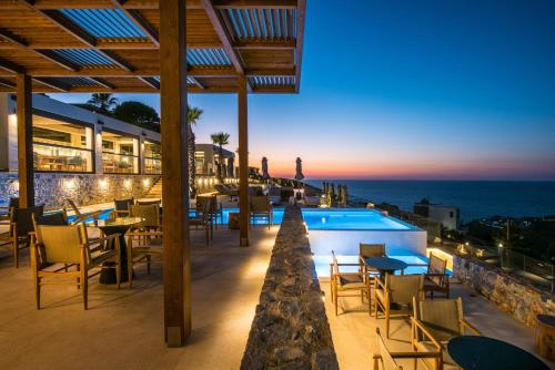 a restaurant with a view of the ocean at night at Happy Cretan Suites in Agia Pelagia