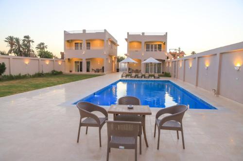 a villa with a swimming pool in front of a house at Royal Nile Villa - Pool View Apartment 1 in Luxor