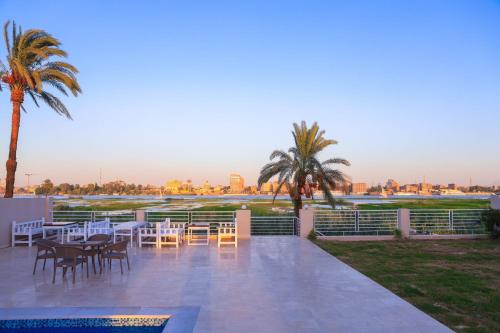 a patio with tables and chairs and palm trees at Royal Nile Villa - Pool View Apartment 1 in Luxor
