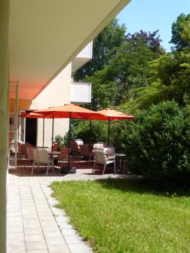 a patio with tables and chairs and umbrellas at Hotel Biederstein am Englischen Garten in Munich