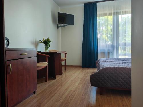 een hotelkamer met een bed, een bureau en een raam bij Pensjonat Lubar in Dziwnów