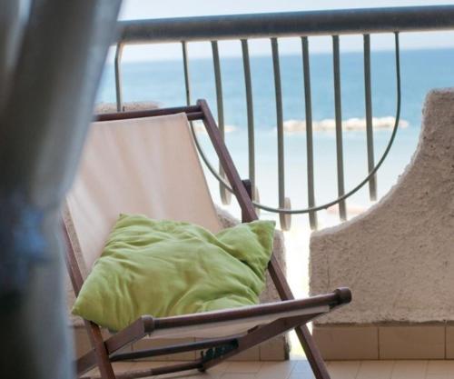 a chair with a green pillow sitting on a balcony at Residence Le Terrazze Sul Mare in San Mauro a Mare
