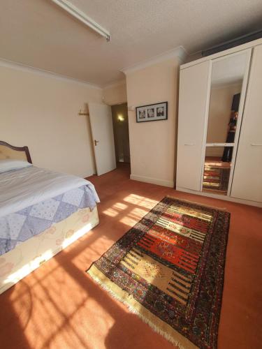 a bedroom with a bed and a rug on the floor at Double bedroom with sitting area fully furnished in Stone Grove