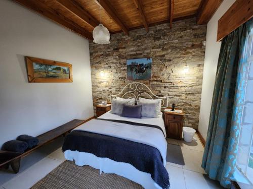 1 dormitorio con cama y pared de piedra en Saxon Park Farm Cottage en Ficksburg