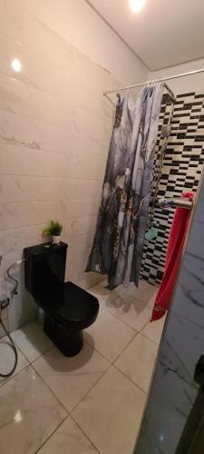 een badkamer met een zwart toilet en een kledingrek bij planets house in Deroua