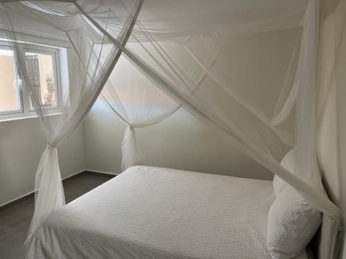 1 dormitorio con cama blanca con dosel y ventana en Cubana Resort Appartement loopafstand Mambo beach, en Willemstad