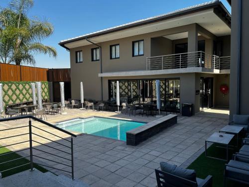 a house with a swimming pool and a patio at Riverleaf Hotel in Brits