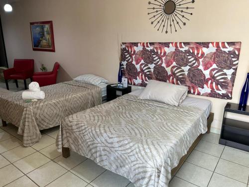 Habitación con 2 camas y silla roja. en Habitaciones Amuebladas Castillo98 en Veracruz