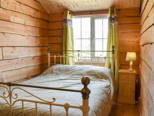 a bedroom with a bed in a log cabin at Brook Lodge in Liskeard