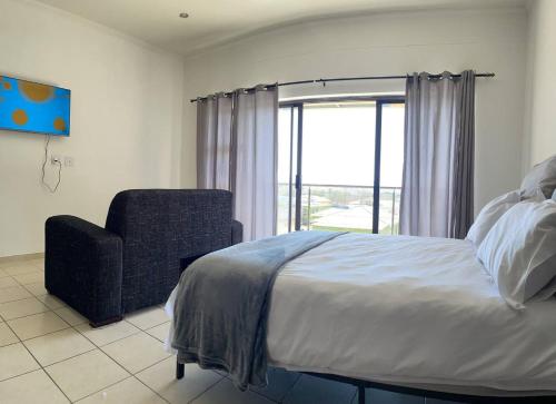 een slaapkamer met een bed, een stoel en een raam bij H&H Self-catering in Windhoek
