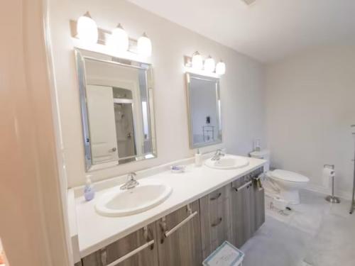 a bathroom with two sinks and a toilet and mirrors at Inspired Stay close to Niagara *4B & 2King Beds* in Thorold